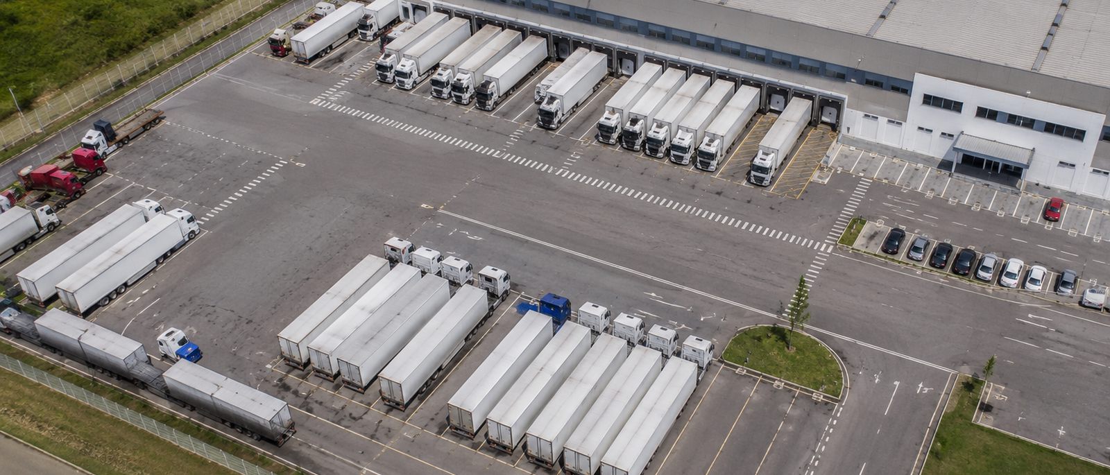 Vista aérea de pátio de galpão logístico com carretas nas docas